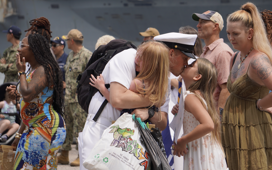 A sailor hugs and kisses his family.